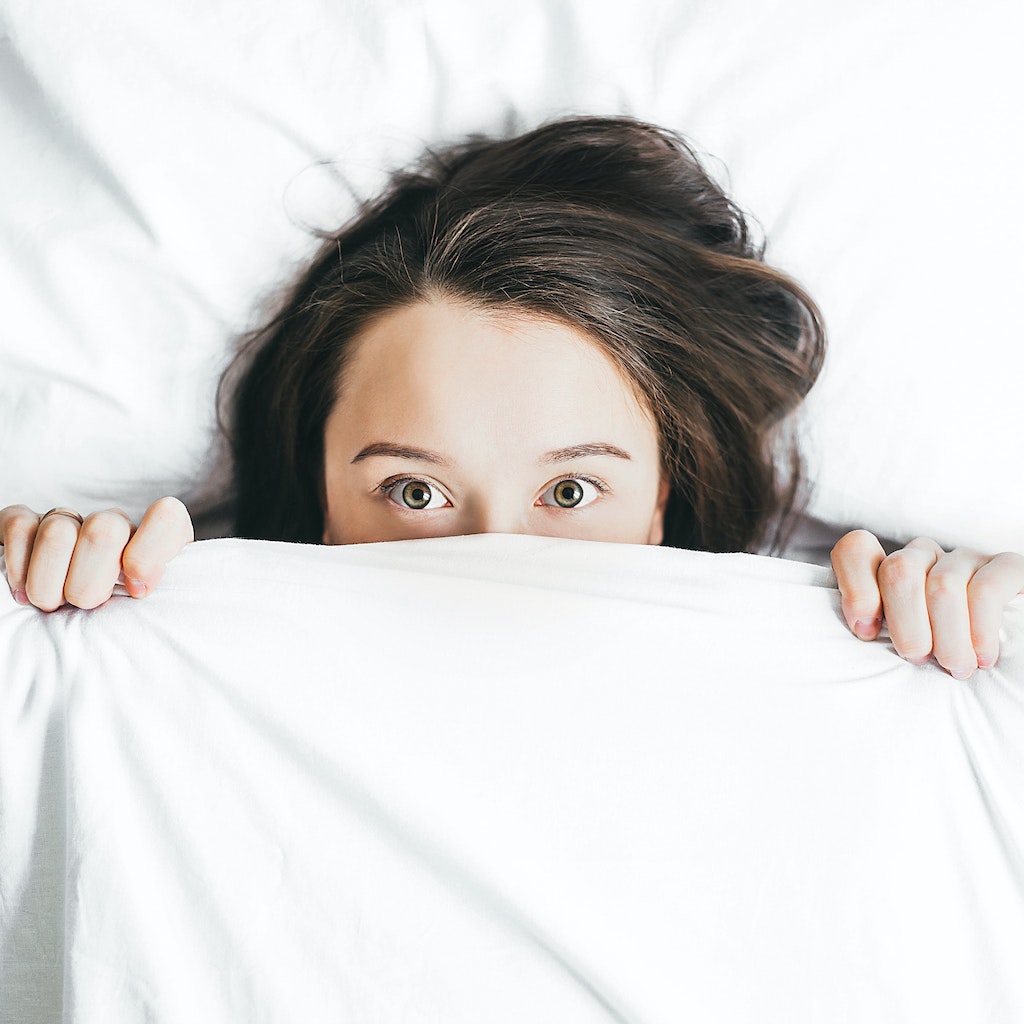 Show a woman experiencing anxiety when trying to sleep